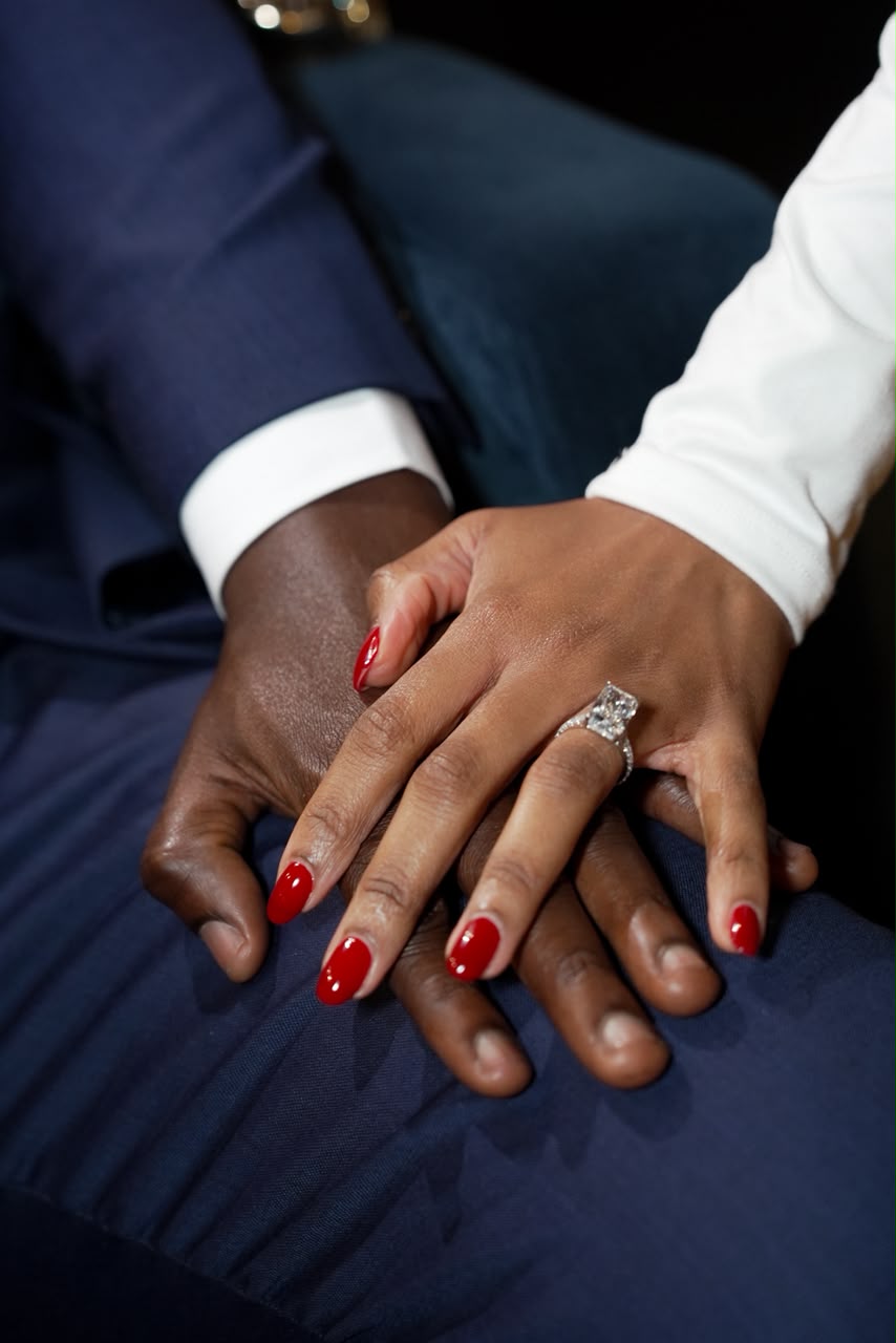 Otobong's hand resting on Harrison's suit